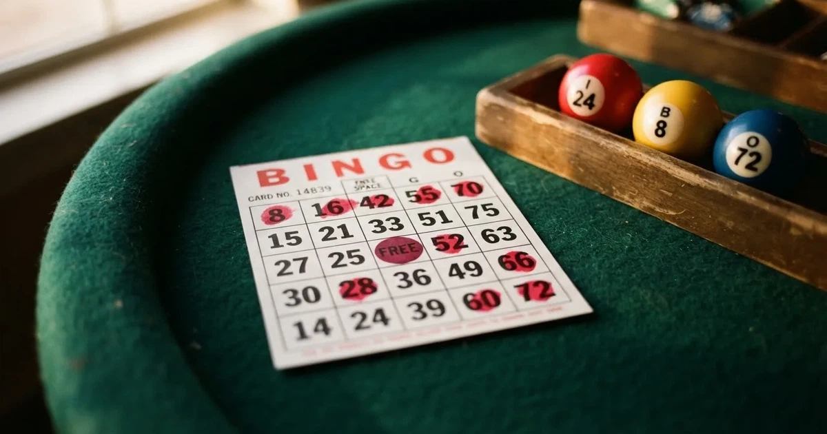 Karta do bingo z odznaczonymi liczbami obok wylosowanych kulek na stole w kasynie online
